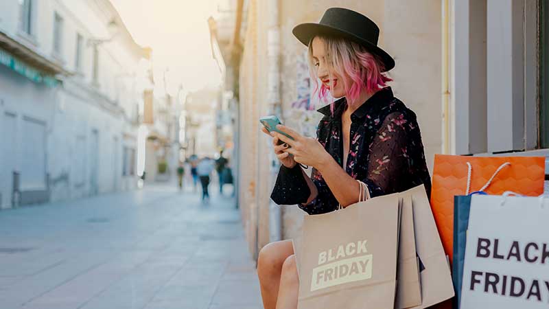 Rapariga com sacos de compras com a inscrição "Black Friaday"